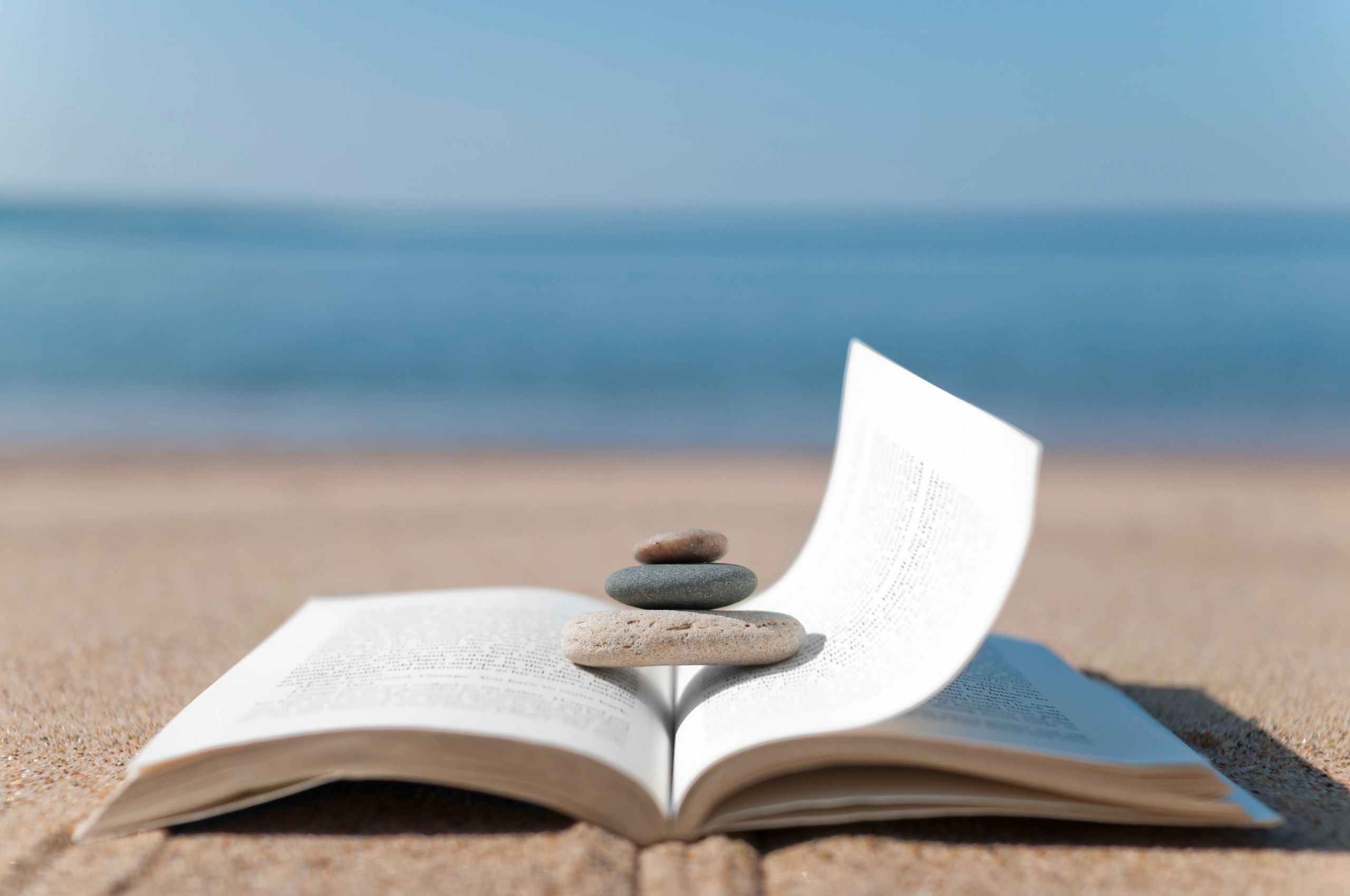Book on a beach with stacked stones in a calm zen setting